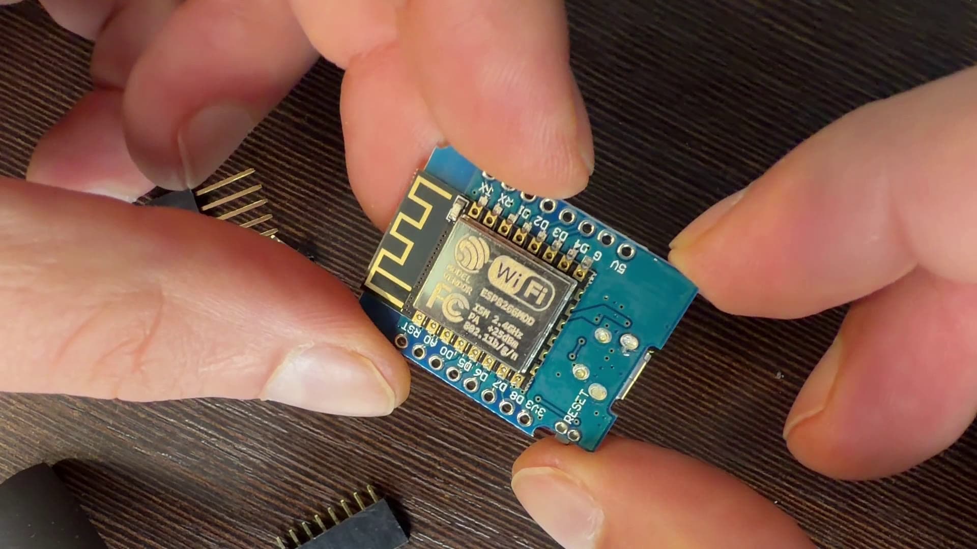 Płytka D1 mini trzymana w palcach, z modułem ESP8266MOD i oznaczeniem Wi-Fi